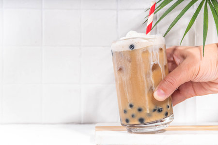 Classic boba bubble tea with tapioca pearls and whipped non-dairy creamer on top of glass, summer cold sweet dessert drink on white table background copy spaceの写真素材