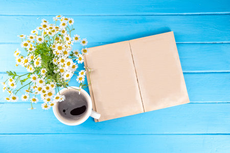 Chamomile daisy flowers bouquet, book, tea or coffee cup, relaxation holiday simple life enjoy summer background, on light blue wood background, top view copy space. Good day, good morning wishingの写真素材