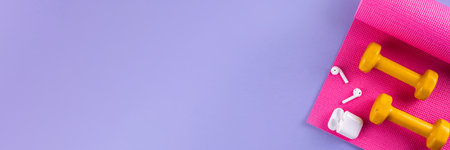 Sport and fitness background. Women's sports accessories. yoga mat with dumbbells, bottle of water, towel, jump rope, headphones, on light purple background, copy spaceの写真素材