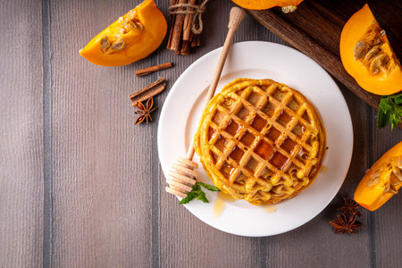 Autumn breakfast dessert, pumpkin waffle. Stack of homemade belgian pumpkin waffles with honey and spices, copy spaceの写真素材