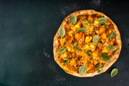 Homemade vegetarian vegetable pizza margarita with pumpkin sauce, pumpkin squash chunks and yellow tomatoes, autumn comfort warm food, copy spaceの写真素材