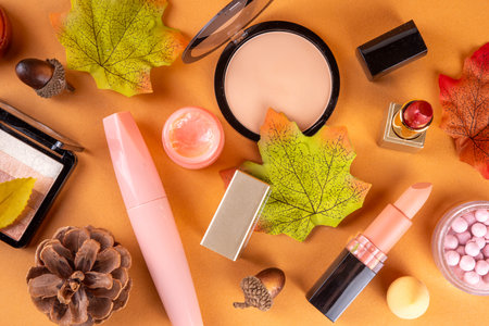 Autumn makeup cosmetics set with cozy beige background with autumn leaves, fall cosmetics sales, autumn seasonal style outlook and makeupの写真素材