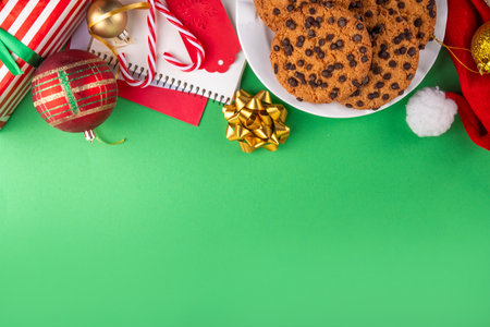 Christmas festive background with tasty hot chocolate, crispy chocolate drops cookies, Christmas decor, baubles, santa hat and gift boxes, high-colored bright red green background copy spaceの写真素材