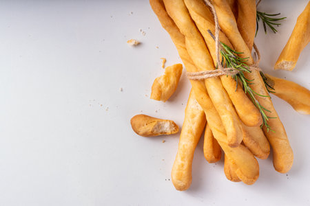 Italian Mediterranean grissini  bread sticks, with aromatic oil and sprigs of rosemary, on a white...