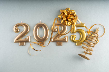 Merry Christmas and Happy New Year 2025 background with golden bauble, Christmas tree balls and decorations, gift bow, serpentine, 2025 golden candles numbers, flat lay top view copy spaceの写真素材