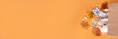 Shopping bag with different pharmacy medicines, capsules and pills with autumn leaves on brown autumn color background. Seasonal fall medicines, cold treatment and autumn health care backgroundの写真素材