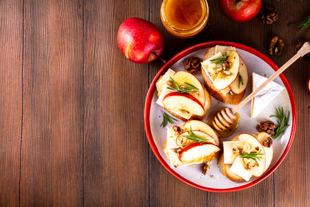 Autumn Apple Brie Crostini with Walnuts and Honey, Fall dinner, Thanksgiving party appetizers idea. Small sandwiches with red apple slices, brie cheese and sweet honey drizzlesの写真素材