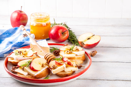 Autumn Apple Brie Crostini with Walnuts and Honey, Fall dinner, Thanksgiving party appetizers idea. Small sandwiches with red apple slices, brie cheese and sweet honey drizzlesの写真素材
