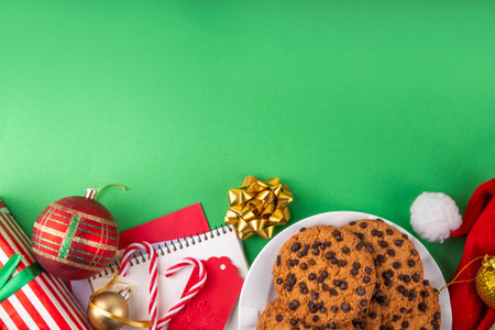 Christmas festive background with tasty hot chocolate, crispy chocolate drops cookies, Christmas decor, baubles, santa hat and gift boxes, high-colored bright red green background copy spaceの写真素材