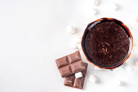 Marzipan hot chocolate, on table with ingredients, marshmallows and marzipan chocolates. Winter and Christmas comfort tasty hot cocoa drink in white cupの写真素材