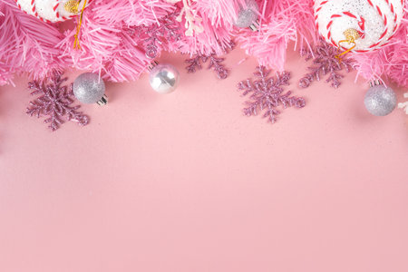 Kitschmas Christmas background with fluffy pink artificial Christmas tree brunches, pink festive bow and decorations in trendy embracing kitsch style, top view flat lay copy spaceの写真素材