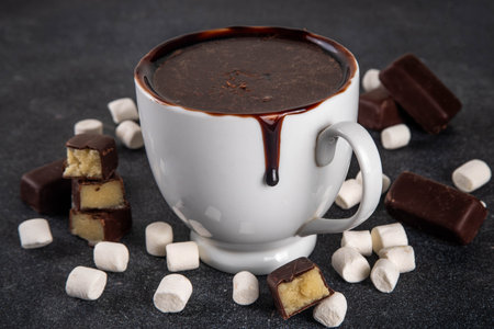 Marzipan hot chocolate, on table with ingredients, marshmallows and marzipan chocolates. Winter and Christmas comfort tasty hot cocoa drink in white cupの写真素材