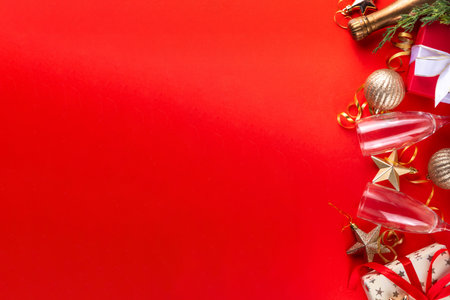 Happy New Year and Merry Christmas Holiday Party invitation background with Champagne glass and bottle, festive decorations, New Year Greeting card flat lay on bright red background, copy spaceの写真素材