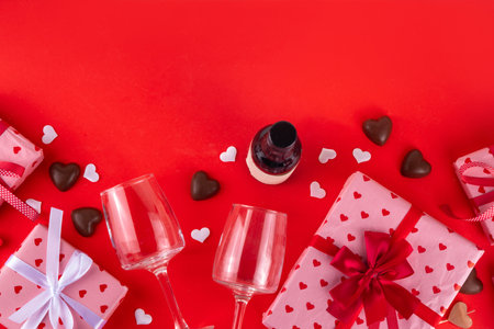 Valentine day greeting card background with chocolates hearts and gift boxes, wine glasses and bottle, on red background. St Valentineâs day dating menu for restaurant, cafes, party invitationの写真素材
