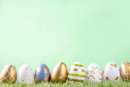 Easter egg and grass background. Funny colorful Easter eggs with bunny rabbit decor and sunny bokeh on grass and light green background. Happy Easter spring holiday greeting card backgroundの写真素材