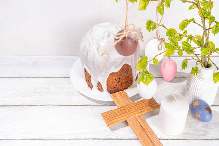 Easter orthodox catholic Christian  holiday background, with wooden cross symbol of religion, baking Easter cake with sugar icing, colored painted eggs and spring branches with blossoming leavesの写真素材