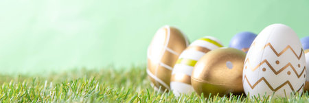 Easter egg and grass background. Funny colorful Easter eggs with bunny rabbit decor and sunny bokeh...