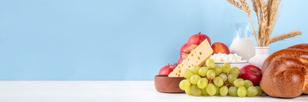 Happy Shavuot holiday background with summer red apples, wheat, grapes, dairy products - cheese, cottage cheese, milk or cream, copy space for textの写真素材