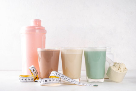 Assortment of different flavors of protein cocktails, with protein powder scoop, measuring tape. Protein shakes for weight loss, set every day protein goals, sport and fitness, healthy lifestyleの写真素材
