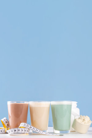 Assortment of different flavors of protein cocktails, with protein powder scoop, measuring tape. Protein shakes for weight loss, set every day protein goals, sport and fitness, healthy lifestyleの写真素材