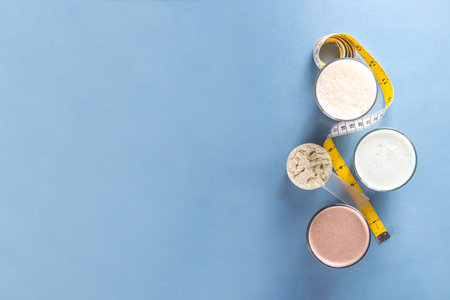 Assortment of different flavors of protein cocktails, with protein powder scoop, measuring tape. Protein shakes for weight loss, set every day protein goals, sport and fitness, healthy lifestyleの写真素材