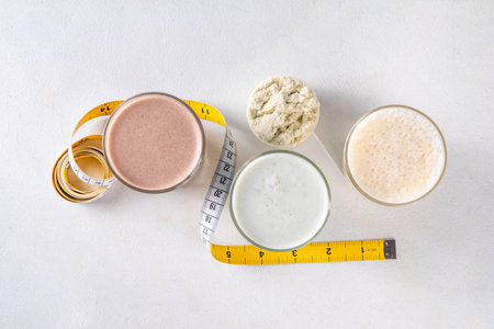 Assortment of different flavors of protein cocktails, with protein powder scoop, measuring tape. Protein shakes for weight loss, set every day protein goals, sport and fitness, healthy lifestyleの写真素材