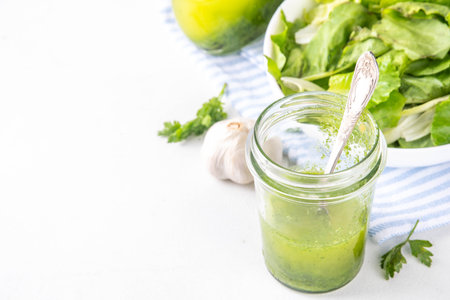 Culinary aromatic Green Herb Salad Dressing. Infused fresh Basil, parsley garlic olive oil for cooking dinner, with green salad on kitchen background copy spaceの写真素材