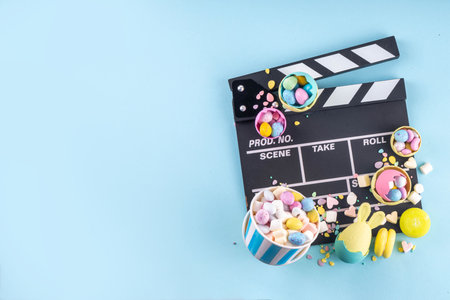 Easter film and movie background. Cinema clapper-board with Easter chocolate egg. popcorn and...