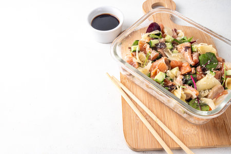 Healthy balanced sushi bowl lunch box with rice, nori, cucumbers, lettuce leaves, salmon fish and...