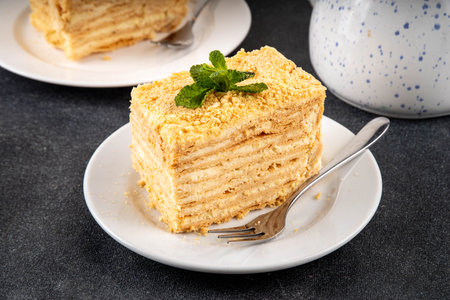 Homemade Napoleon cake slices, layered mille-feuille cake with vanilla creamy custard, tasty delicious puff pastry, on serving plates with forks, copy spaceの写真素材