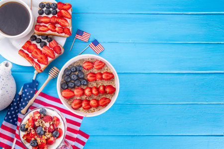 USA patriotic breakfast or brunch with american flag decorated oatmeal, layered yogurt granola dessert, toast sandwiches with fresh berries, and coffee cup on kitchen garden tableの写真素材