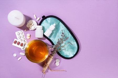 Sleep quality improvement concept, with sleep mask, relaxing herbal tea, lavender, alternative medicine pills for treating sleep disorderの写真素材