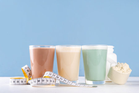 Assortment of different flavors of protein cocktails, with protein powder scoop, measuring tape. Protein shakes for weight loss, set every day protein goals, sport and fitness, healthy lifestyleの写真素材