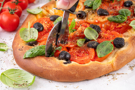 Tomatoes and olives homemade vegetable focaccia, with basil and olive oil. Italian fast food, homemade savory pastries, vegan bread snack with vegetables, antipasto foodの写真素材