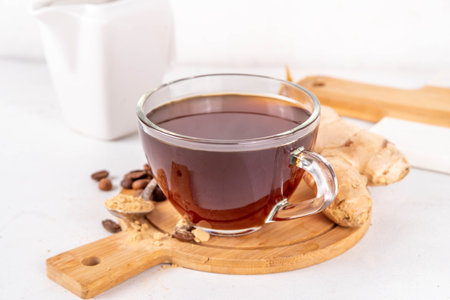 Fresh brewed ginger coffee cup. Dark coffee espresso hot drink with ginger powder and ginger root, on white background. Healthy hot drink. alternative medicine, remedyの写真素材