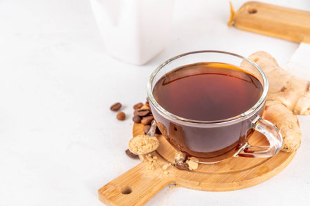Fresh brewed ginger coffee cup. Dark coffee espresso hot drink with ginger powder and ginger root, on white background. Healthy hot drink. alternative medicine, remedyの写真素材