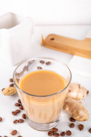 Fresh brewed ginger coffee latte cup. Creamy hot drink with ginger powder and ginger root, on white background. Healthy hot beverage.の写真素材
