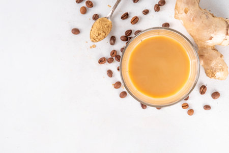 Fresh brewed ginger coffee latte cup. Creamy hot drink with ginger powder and ginger root, on white background. Healthy hot beverage. alternative medicine, remedyの写真素材