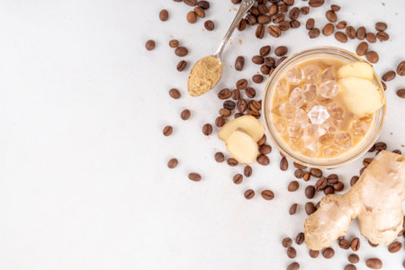 Cold brewed ginger coffee latte cup. Creamy iced drink with ginger powder and ginger root, on white background. Healthy hot beverage.の写真素材