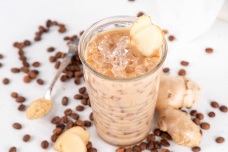 Cold brewed ginger coffee latte cup. Creamy iced drink with ginger powder and ginger root, on white background. Healthy hot beverage.の写真素材
