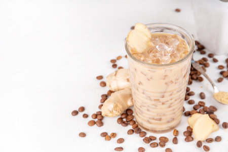 Cold brewed ginger coffee latte cup. Creamy iced drink with ginger powder and ginger root, on white background. Healthy hot beverage.の写真素材