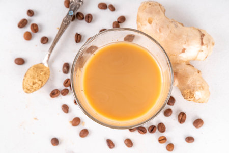 Fresh brewed ginger coffee latte cup. Creamy hot drink with ginger powder and ginger root, on white background. Healthy hot beverage. alternative medicine, remedyの写真素材