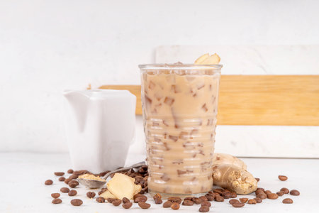 Cold brewed ginger coffee latte cup. Creamy iced drink with ginger powder and ginger root, on white background. Healthy hot beverage.の写真素材
