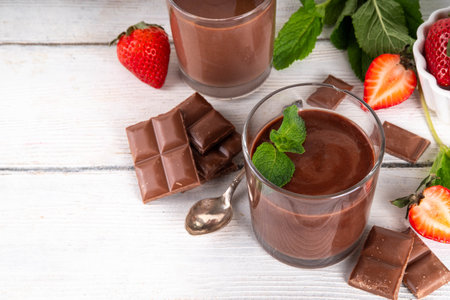 Homemade chocolate pudding dessert, in ceramic portioned bowl on kitchen table, with fresh strawberries, mint and chocolate slicesの写真素材