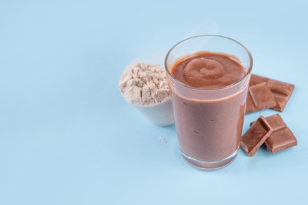 Quick and simple protein pudding. Healthy summer cold dessert. Three glasses with vanilla, chocolate and berry protein pudding, with chocolate slices, fresh strawberry, blueberry, protein powder scoopの写真素材