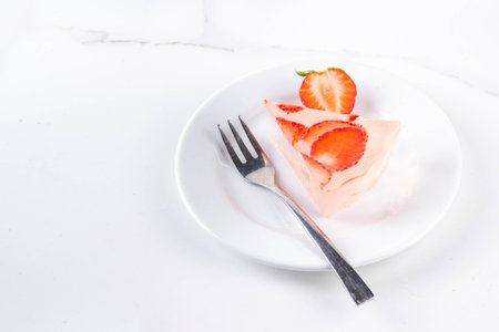 Japanese Raindrop Cake, or Mizu Shingen Mochi, clear jelly dessert, crystal-clear water-like delicacy agar pudding tart with strawberry slices, portioned on plates, white marble background copy spaceの写真素材
