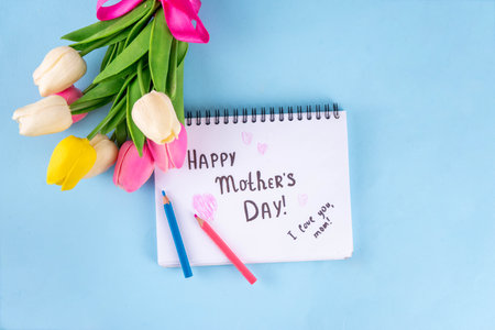 Mother day greeting card, brunch or party invitation background, Spring bouquet of tulip flower, with gift bow and note Happy Mothers day, copy space on colorful light blue backgroundの写真素材