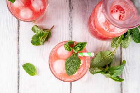 Homemade watermelon lemonade, sweet refreshing summer drink, iced watermelon juice with mint decor and striped straw, light blue and wooden background, copy spaceの写真素材