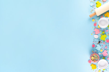 Easter baking background with sugar sprinkles, sugar Easter bunny, easter egg and spring flowers decoration, rolling pin and bakery accessories, light blue background top view copy spaceの写真素材