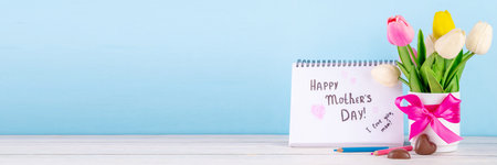 Mother day greeting card, brunch or party invitation background, Spring bouquet of tulip flower, with gift bow and note Happy Mothers day, copy space on colorful light blue backgroundの写真素材